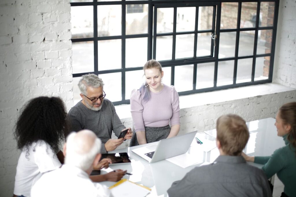 From above view of positive multiethnic coworkers sitting together around table with gadgets and documents and discussing business strategy while working in modern office